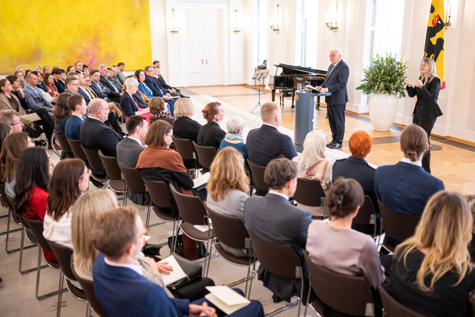 Bundespräsident Frank-Walter Steinmeier steht vor den Gästen im Großen Saal am Pult und hält eine Ansprache, neben ihm steht eine Gebärdendolmetscherin